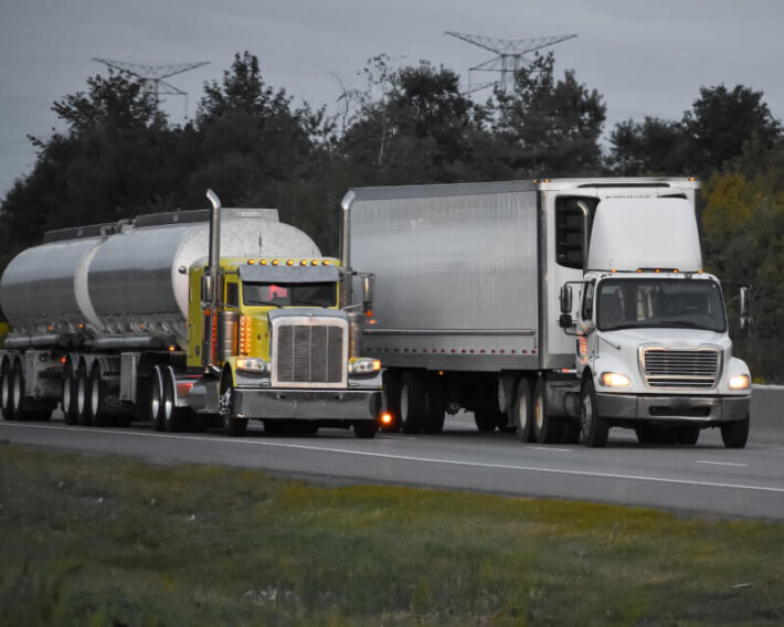 A delivery truck and liquid storage truck passing on a highway.