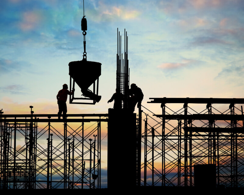 Three workers on a drill site maneuvering a funnel shaped attachment from a crane.