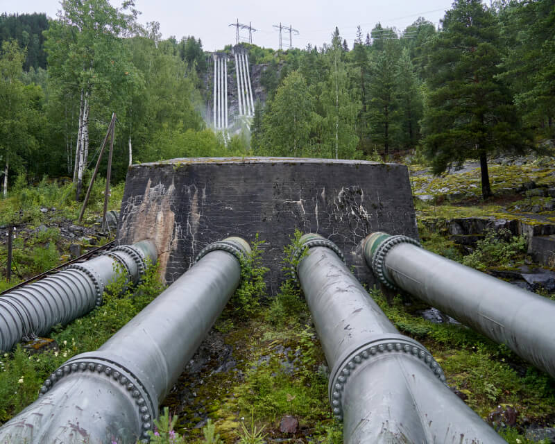 Long large gray metal pipes running through a green field