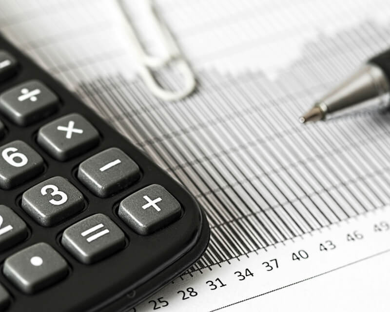 Calculator and pen poised on a paper line graph.