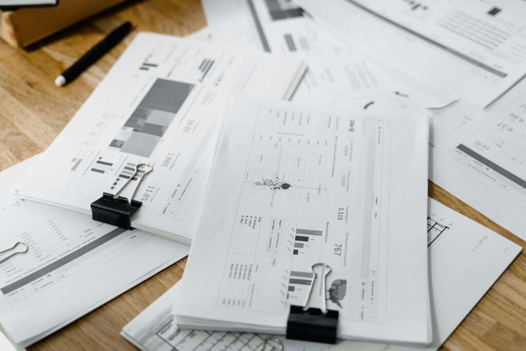 Binder-clipped papers showing financial graphs and charts on a desk.