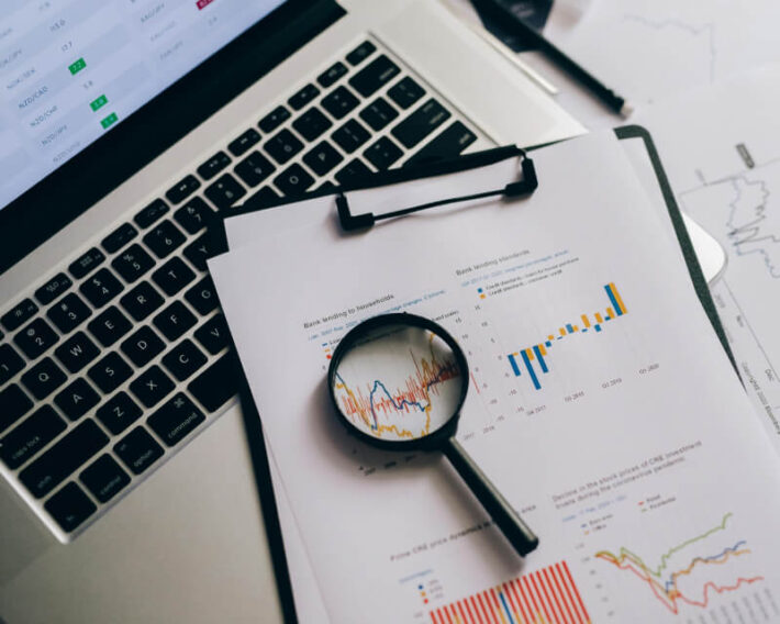 Printed graphs and charts lying on laptop keyboard.