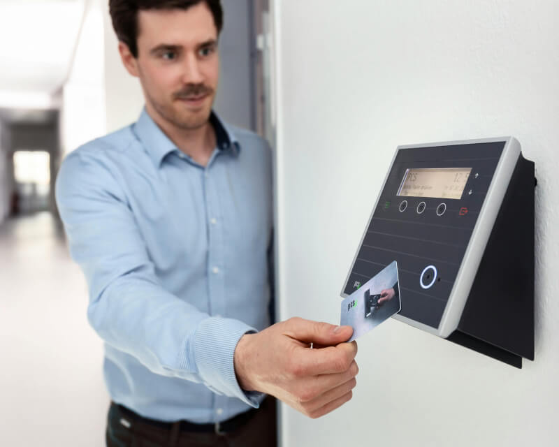 Employee in long hallway using key card.