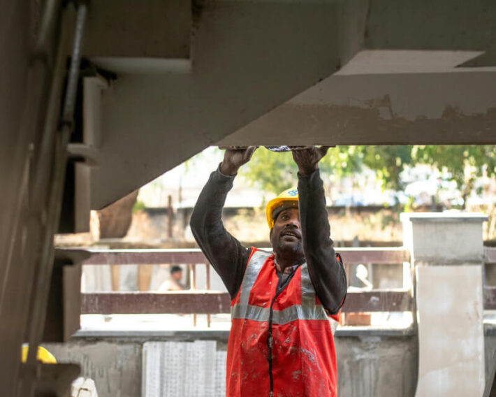 Construction worker in red safety vest repairing concrete stairs.