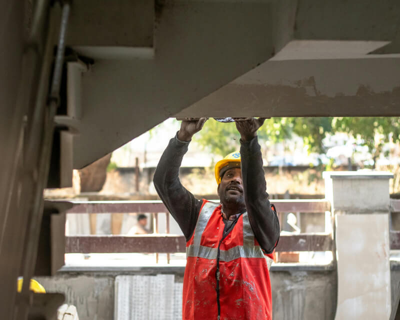 Construction worker in red safety vest repairing concrete stairs.