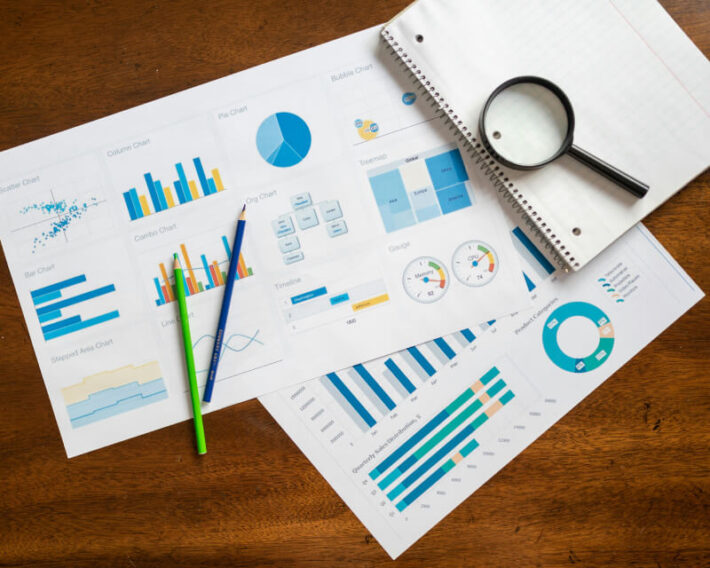 Colorful graphs and charts on a desk with pencils and a notebook.