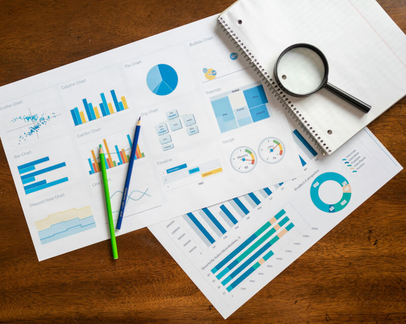 Colorful graphs and charts on a desk with pencils and a notebook.